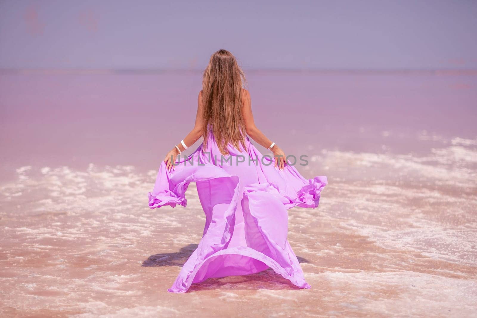 Woman pink salt lake. Against the backdrop of a pink salt lake, a woman in a long pink dress takes a leisurely stroll along the white, salty shore, capturing a wanderlust moment. by Matiunina