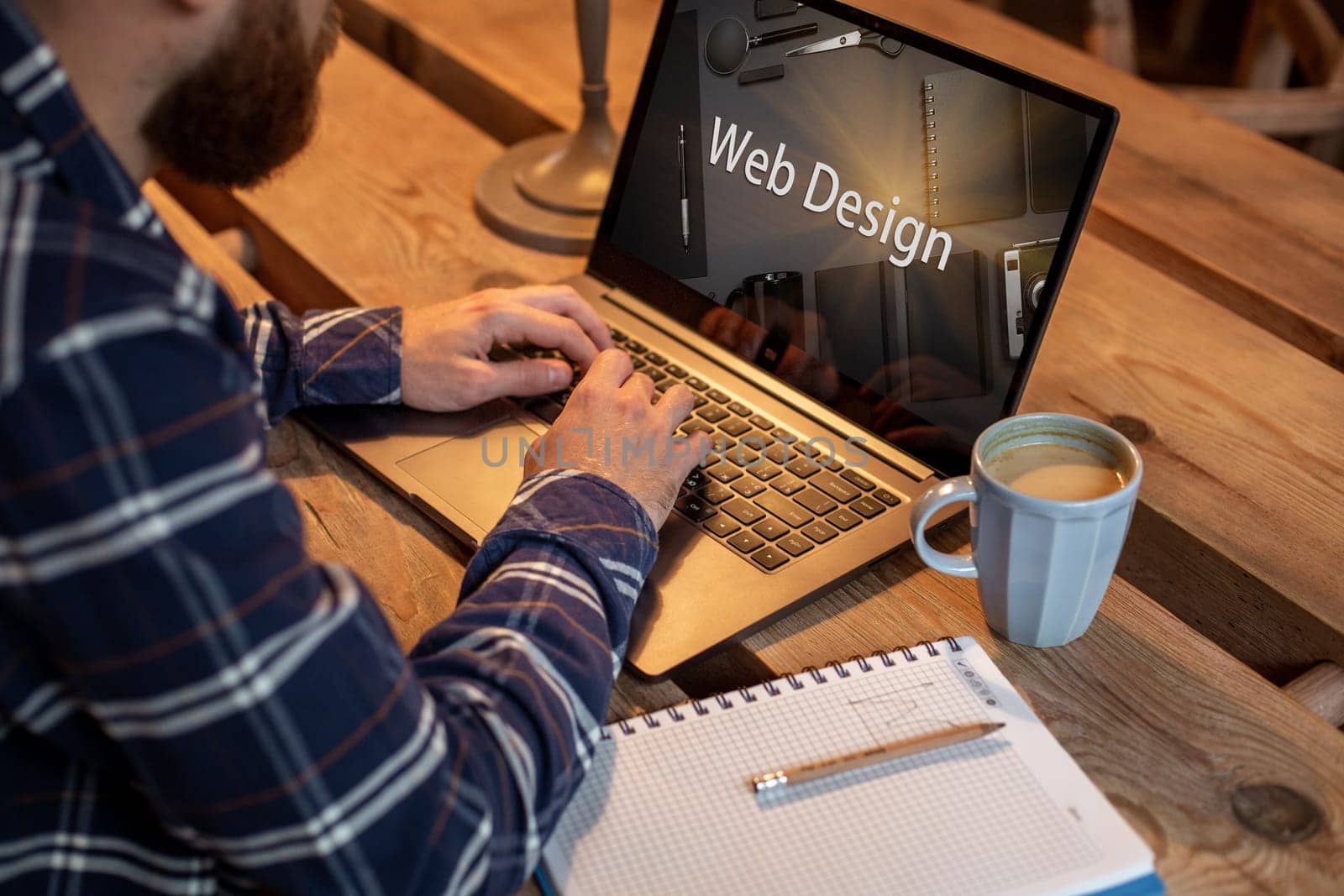 Cropped image of a young man working on his laptop in a coffee shop, rear view of business man hands busy using laptop at office desk, young male student texting on computer sitting at wooden table. Design. Web design