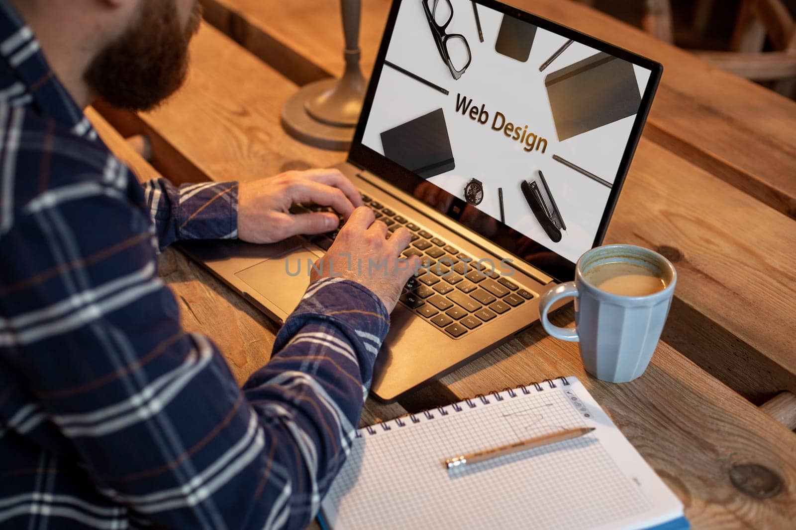 Cropped image of a young man working on his laptop in a coffee shop, rear view of business man hands busy using laptop at office desk, young male student texting on computer sitting at wooden table. Design. Web design