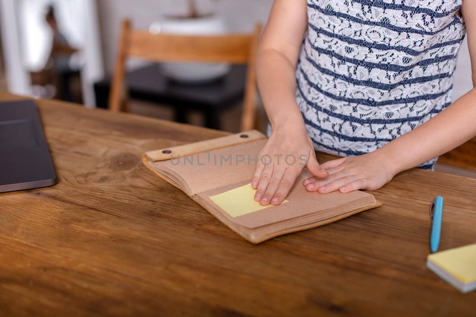 Cute little girl is sitting at table with her notebook. The concept of new programs for teaching children