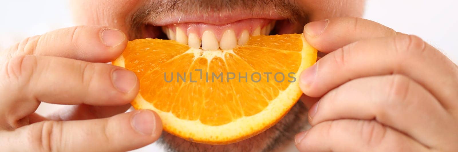 Portrait of smiling man with slice of juicy orange by kuprevich