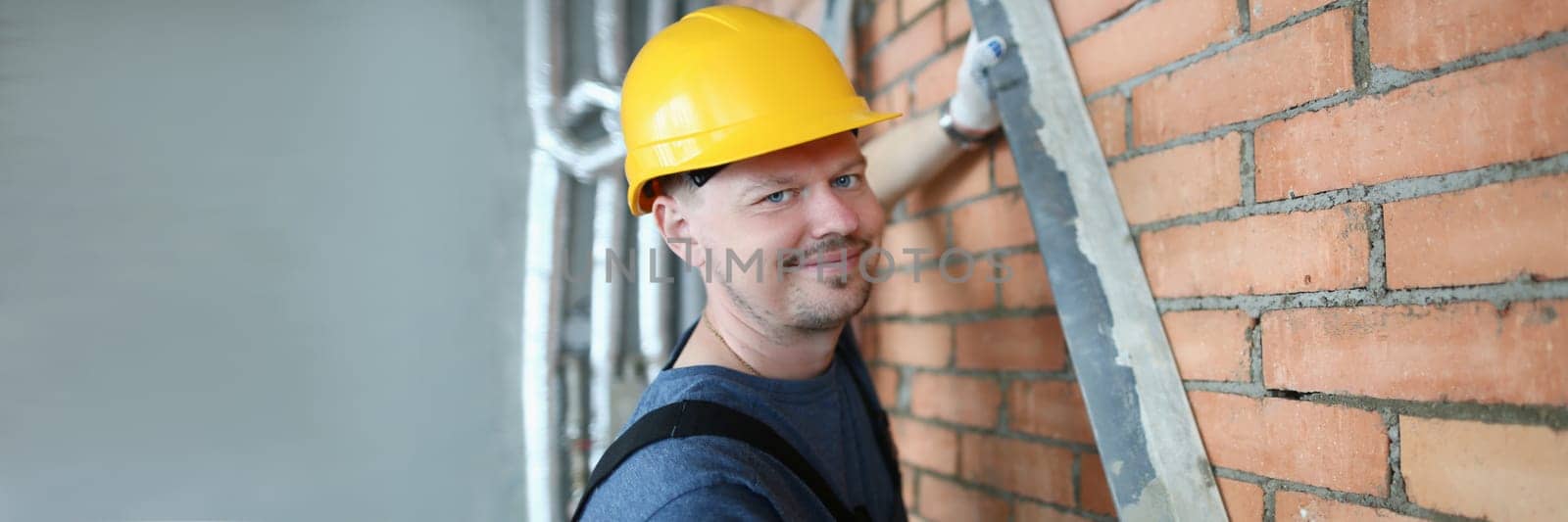 Male builder mason makes brickwork of walls and holds working tool by kuprevich