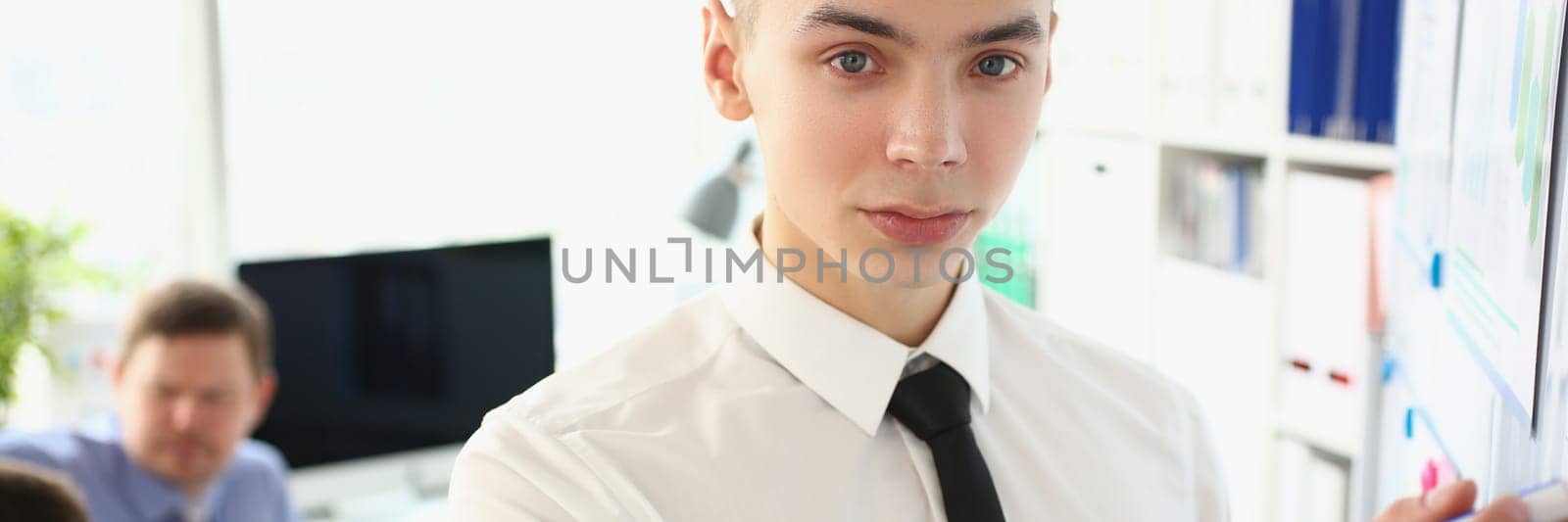 Portrait of man stands with marker near educational white board and holds business lecture by kuprevich