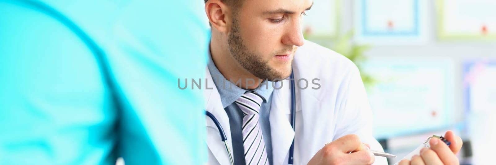 Male doctor looks at patient medical record in clinic. Medical insurance examination and diagnosis concept