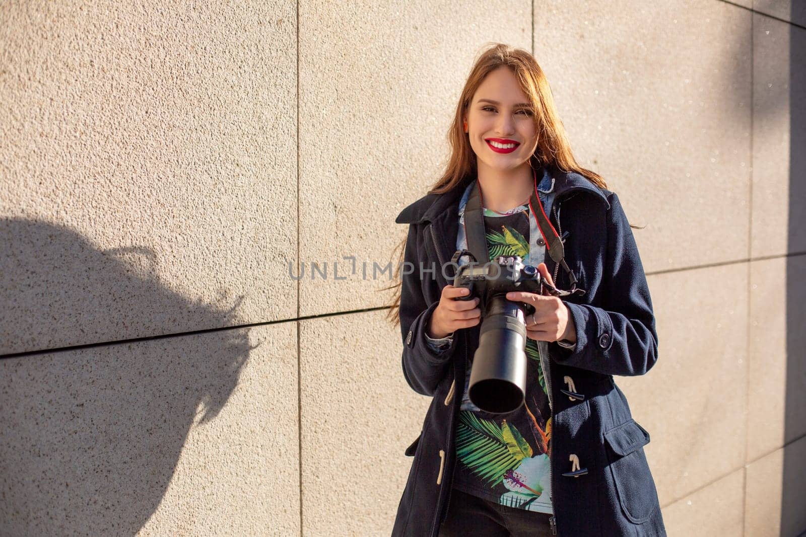 Portrait of professional female photographer on the street photographing on a camera. by nazarovsergey