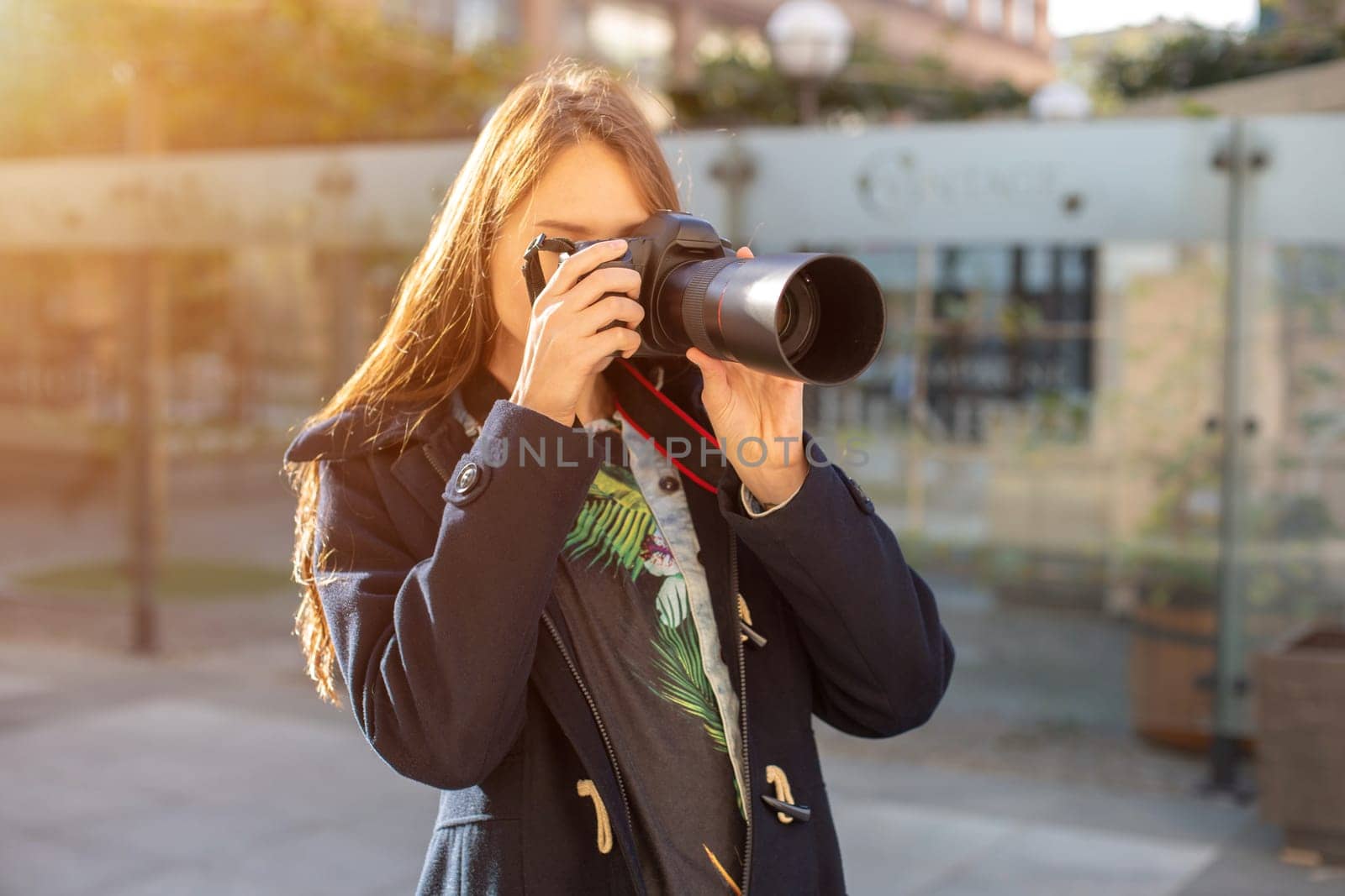 Portrait of professional female photographer on the street photographing on a camera. Photo shoot photosession in the city