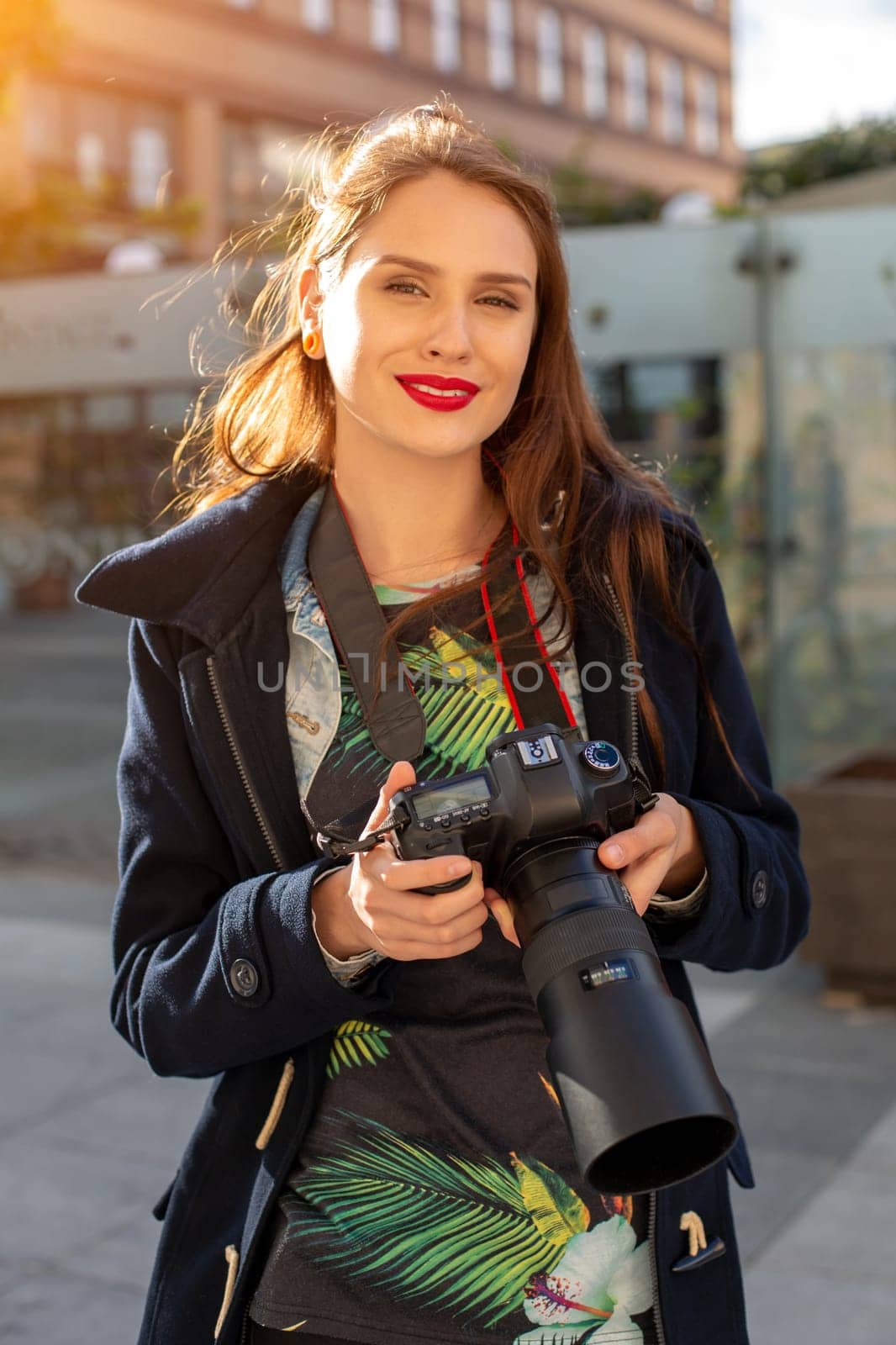 Portrait of professional female photographer on the street photographing on a camera. Photo shoot photosession in the city