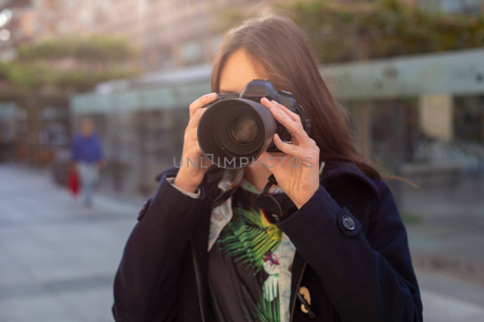 Portrait of professional female photographer on the street photographing on a camera. Photo shoot photosession in the city