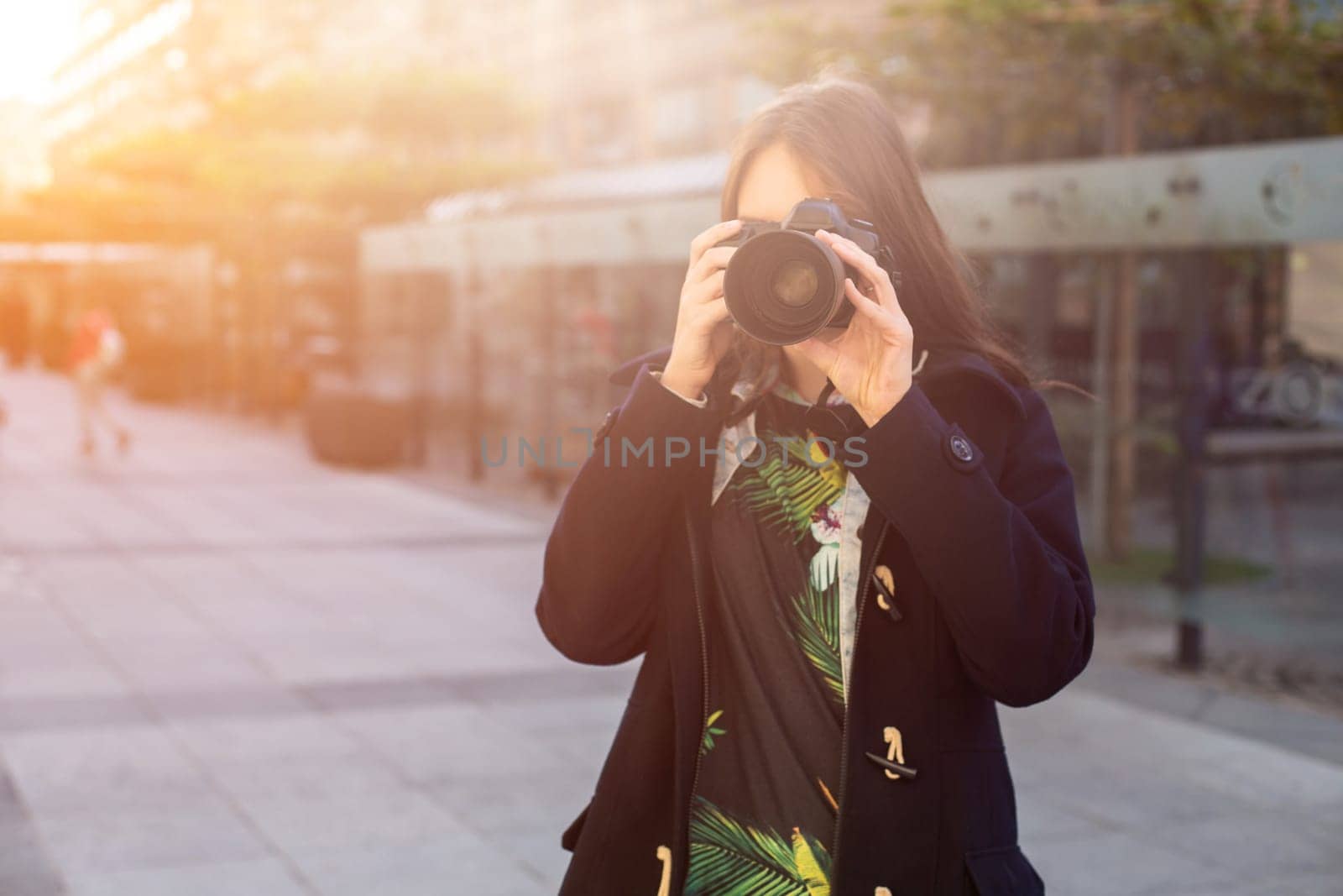 Portrait of professional female photographer on the street photographing on a camera. Photo shoot photosession in the city