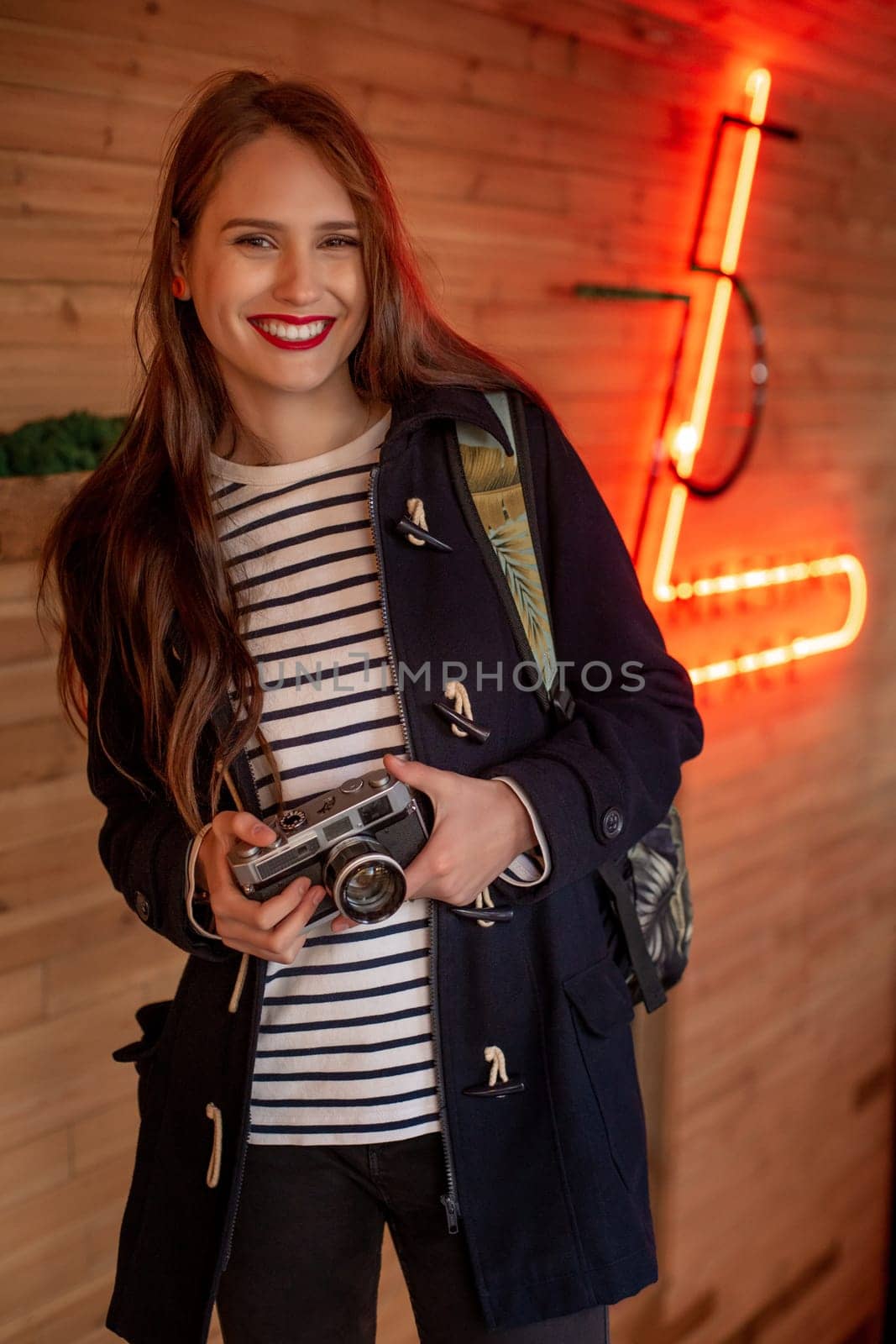 Happy young hipster woman holds retro photo camera. Having fun in the city with camera, travel photo of photographer.