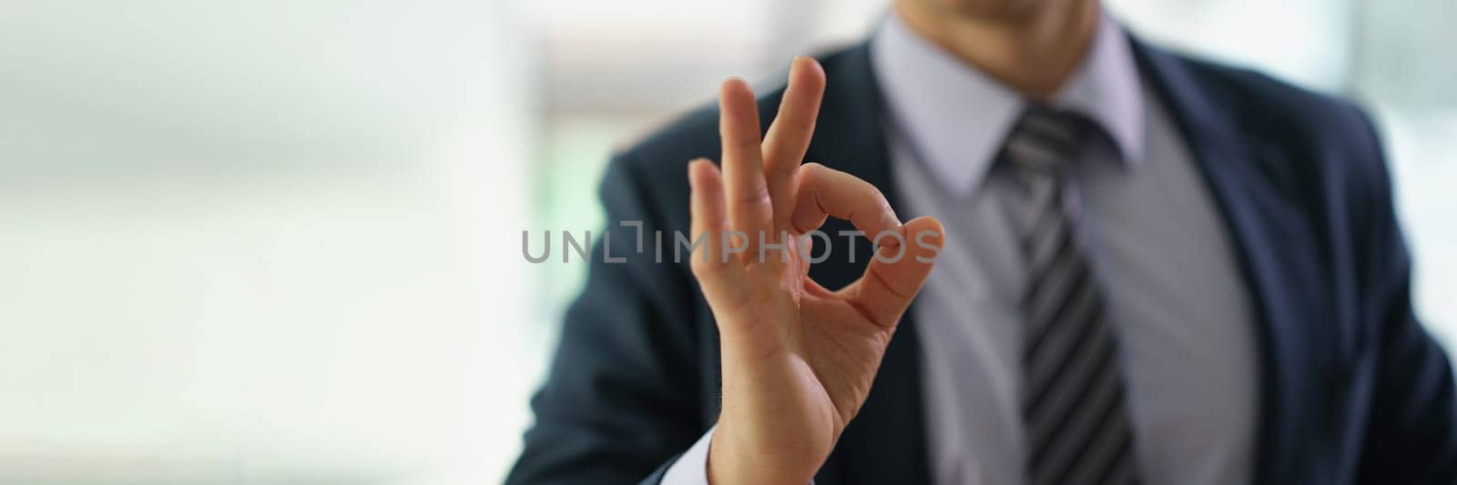 Businessman in suit showing hand gesture ok at work in office closeup by kuprevich