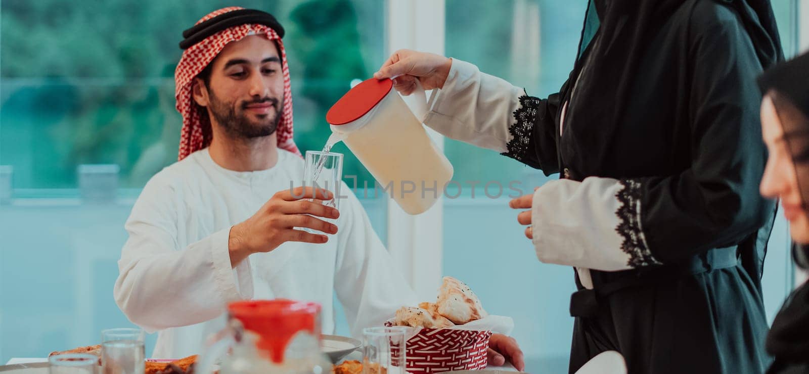 Muslim family having Iftar dinner drinking water to break feast. Eating traditional food during Ramadan feasting month at home. The Islamic Halal Eating and Drinking in modern home by dotshock
