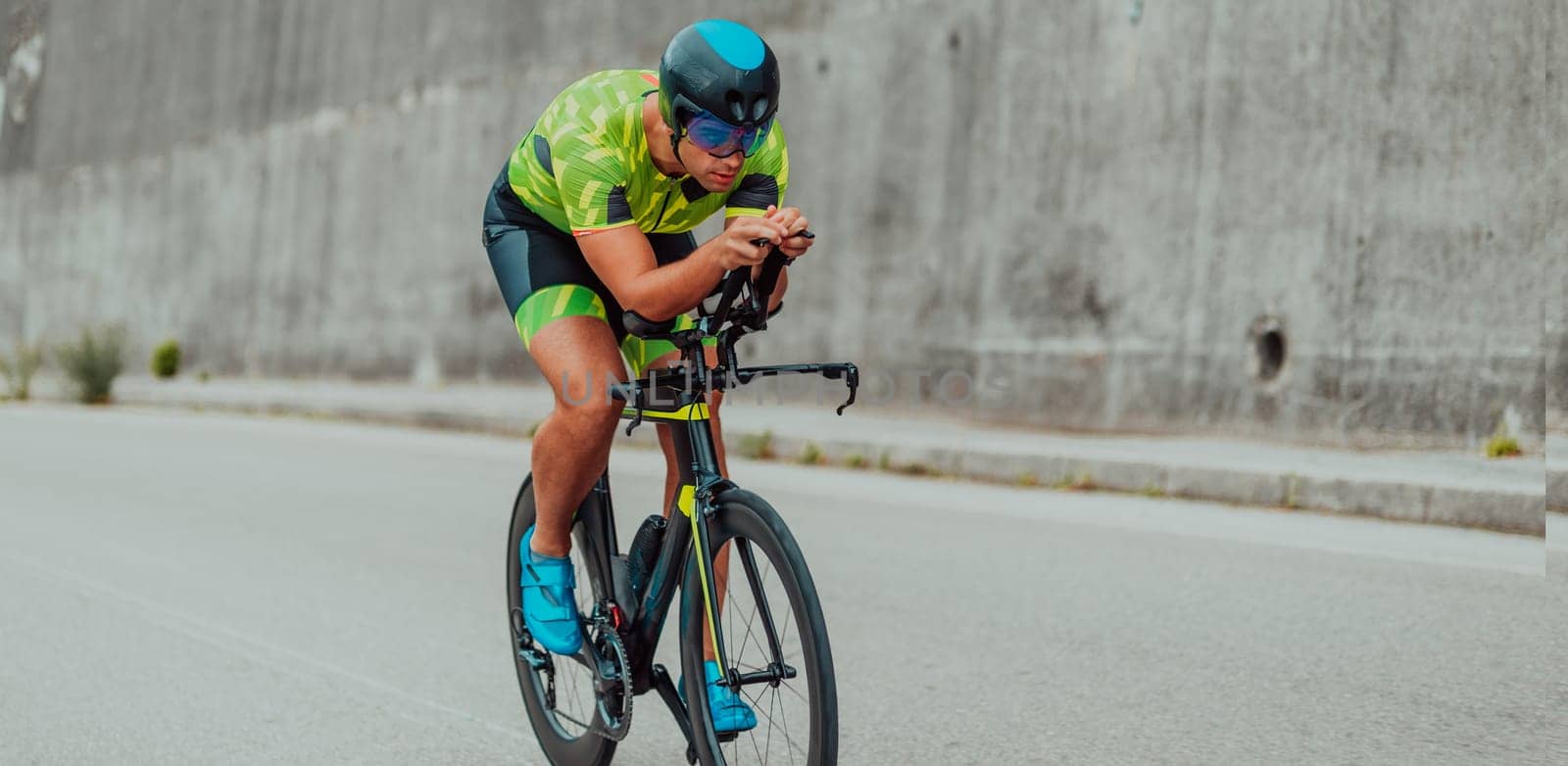 Full length portrait of an active triathlete in sportswear and with a protective helmet riding a bicycle. Selective focus by dotshock