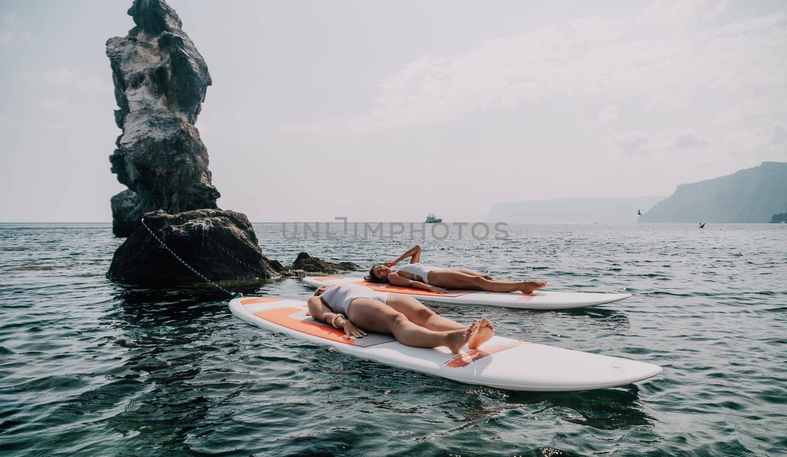 Woman sup yoga. Middle age sporty woman practising yoga pilates on paddle sup surfboard. Female stretching doing workout on sea water. Modern individual hipster outdoor summer sport activity