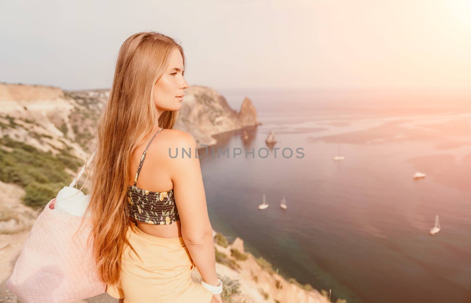 Woman travel sea. Happy tourist taking picture outdoors for memories. Woman traveler looks at the edge of the cliff on the sea bay of mountains, sharing travel adventure journey.