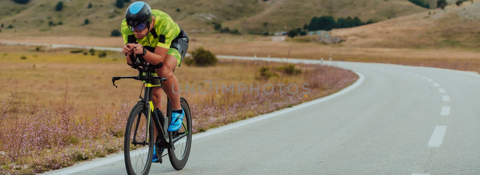 Full length portrait of an active triathlete in sportswear and with a protective helmet riding a bicycle. Selective focus by dotshock