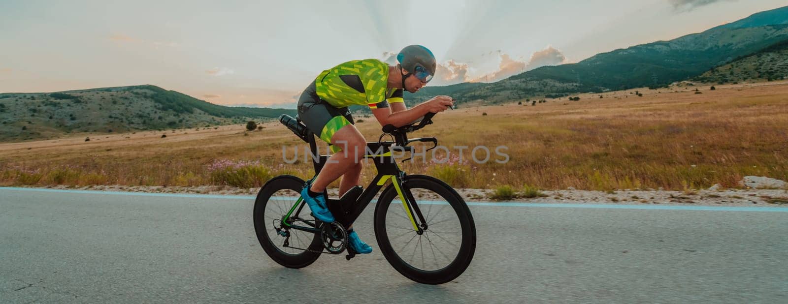 Full length portrait of an active triathlete in sportswear and with a protective helmet riding a bicycle. Selective focus by dotshock