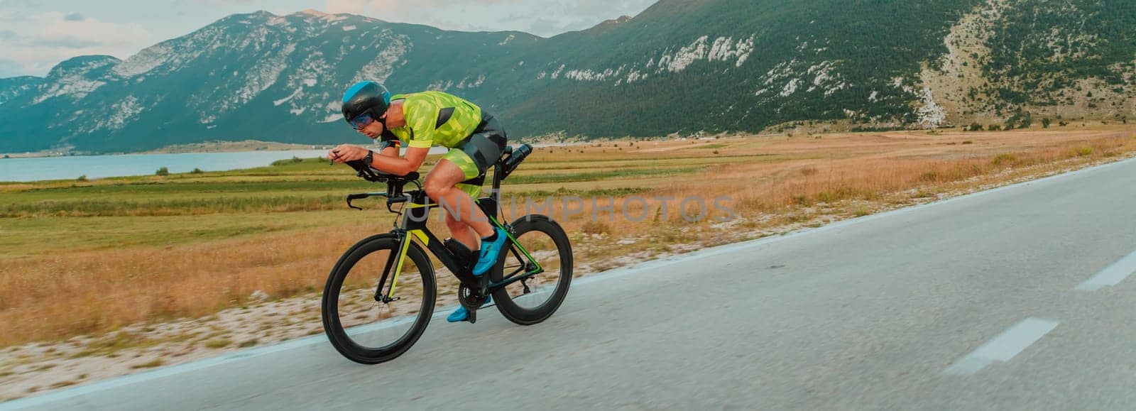 Full length portrait of an active triathlete in sportswear and with a protective helmet riding a bicycle. Selective focus by dotshock