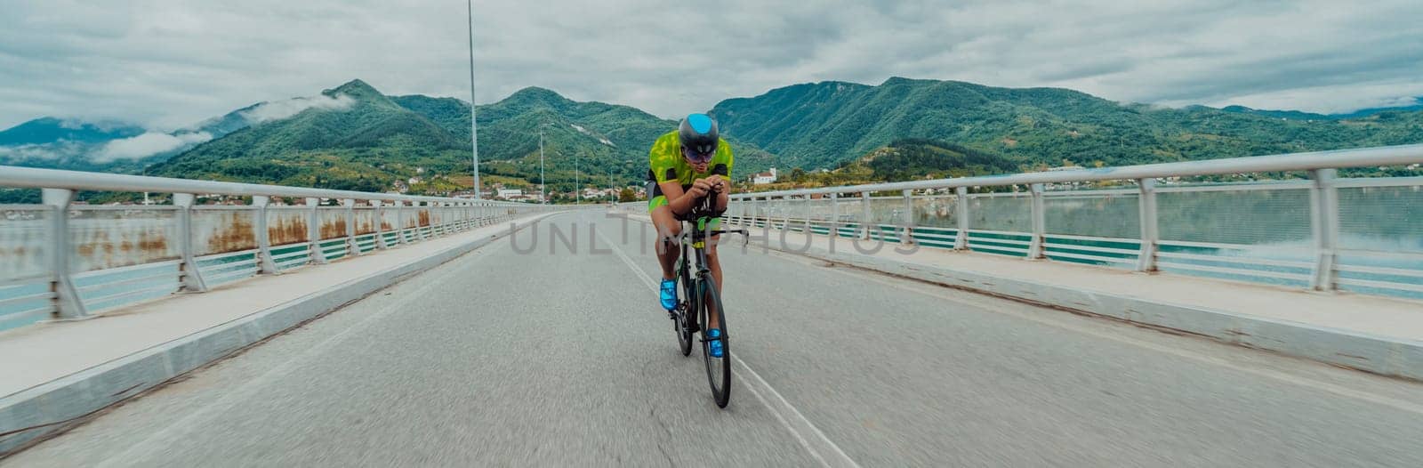 Full length portrait of an active triathlete in sportswear and with a protective helmet riding a bicycle. Selective focus .