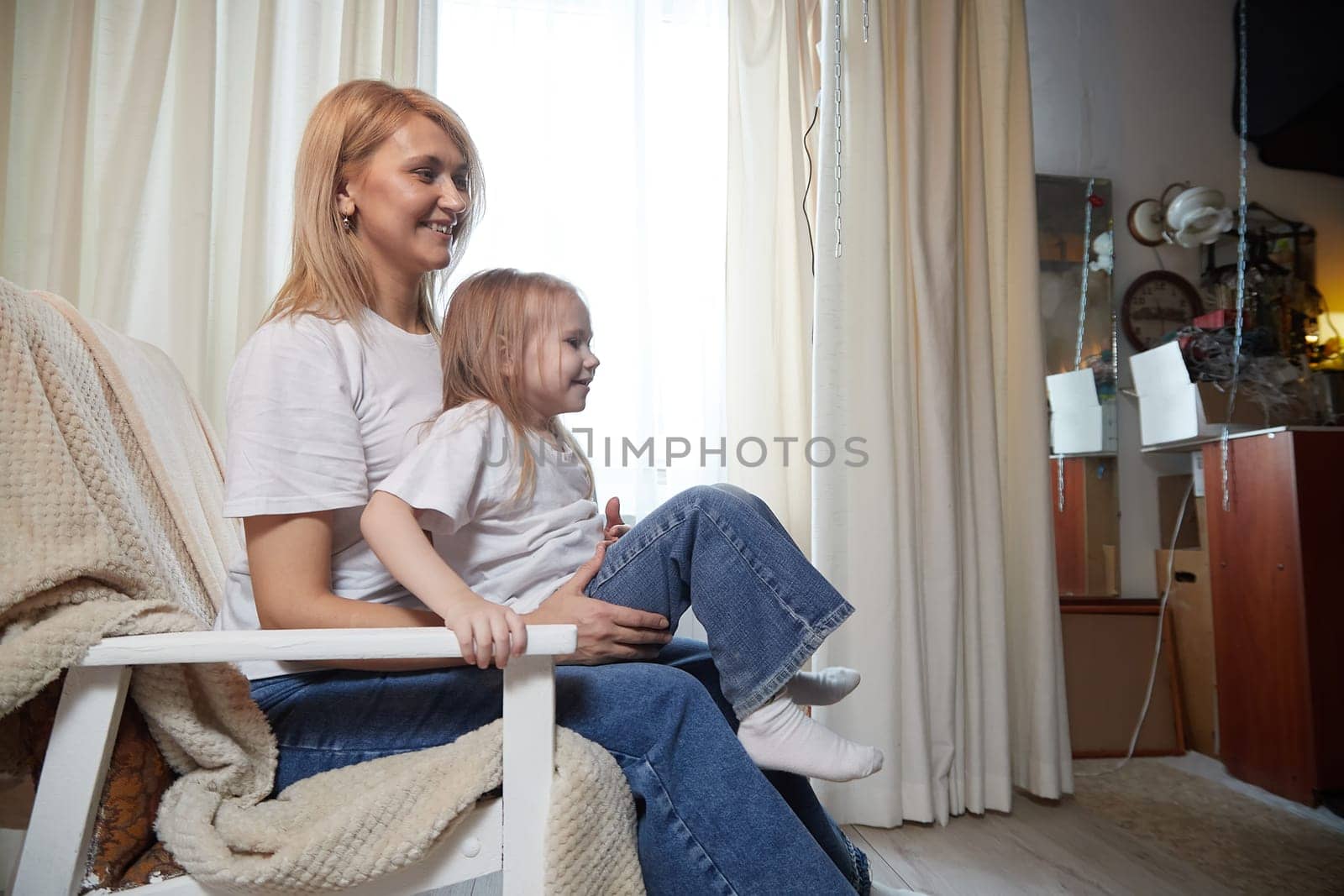 Happy loving family with mother and daughter in living room. Woman mom and small child girl playing and having convercation inside of home