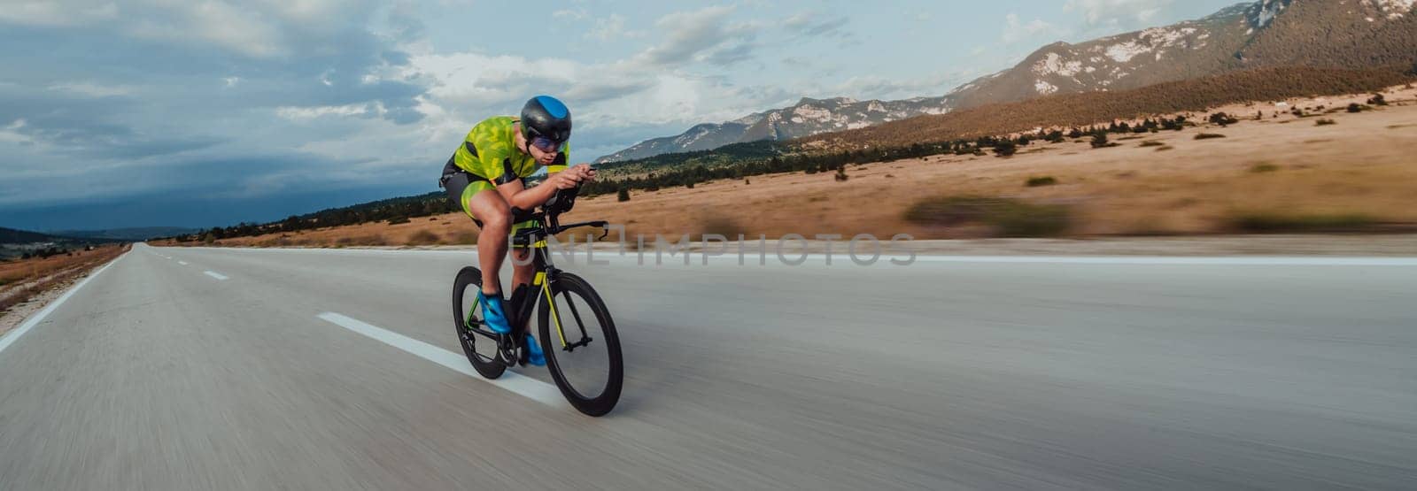 Full length portrait of an active triathlete in sportswear and with a protective helmet riding a bicycle. Selective focus by dotshock