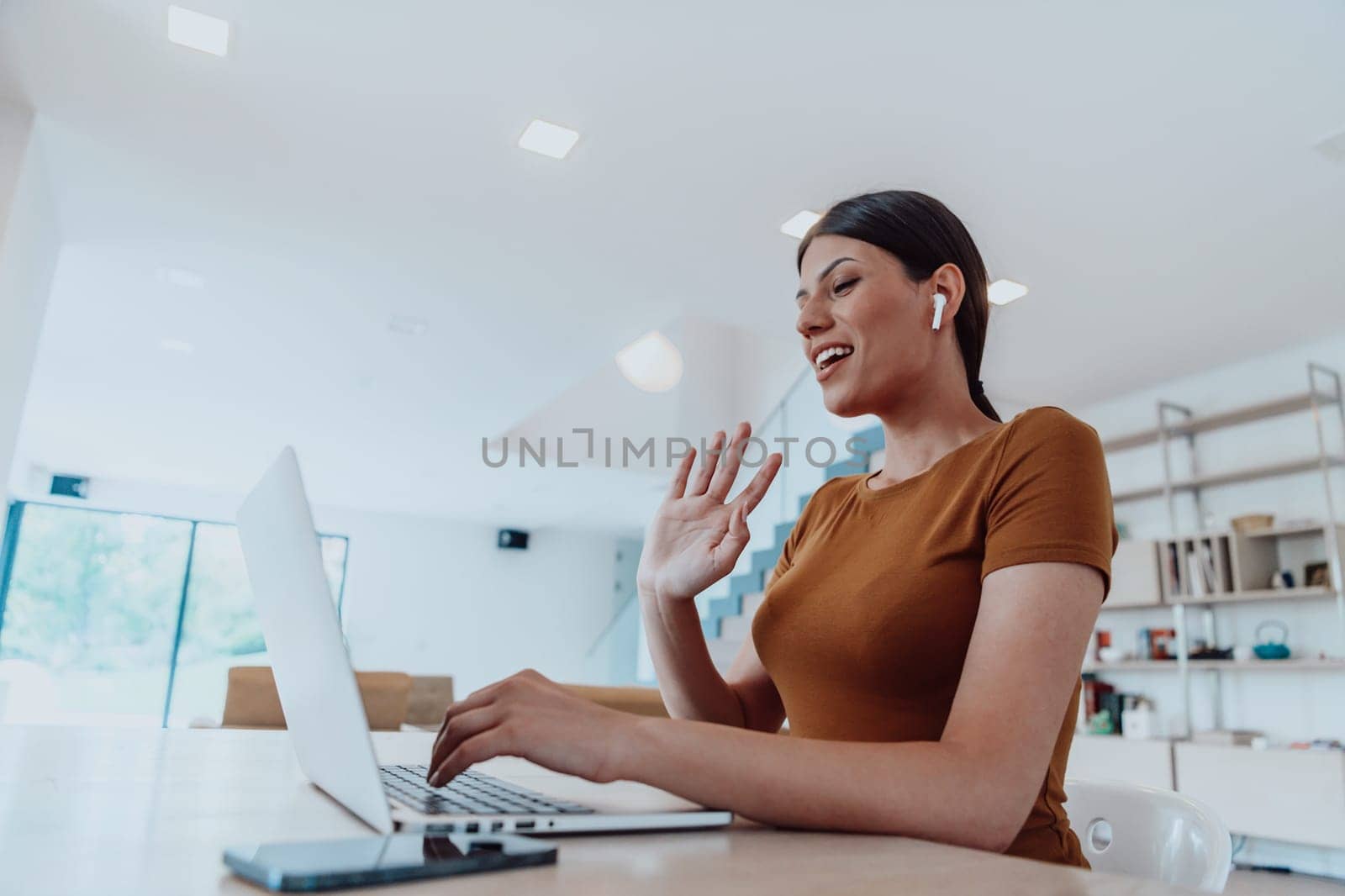 Woman sitting in living room using laptop look at cam talk by video call with business friend relatives, head shot. Job interview answering questions. by dotshock