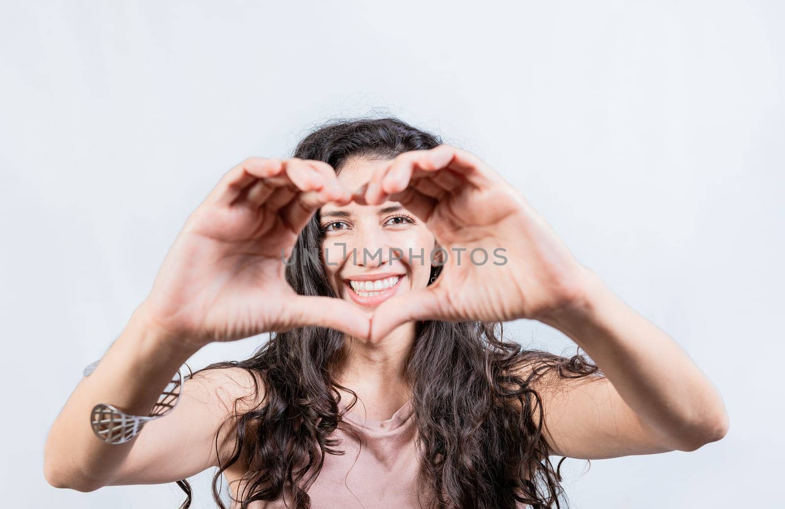 Happy girl making heart shape with hands isolated. Smiling young woman making heart shape with her hands. Teen girl making heart shape with her hands