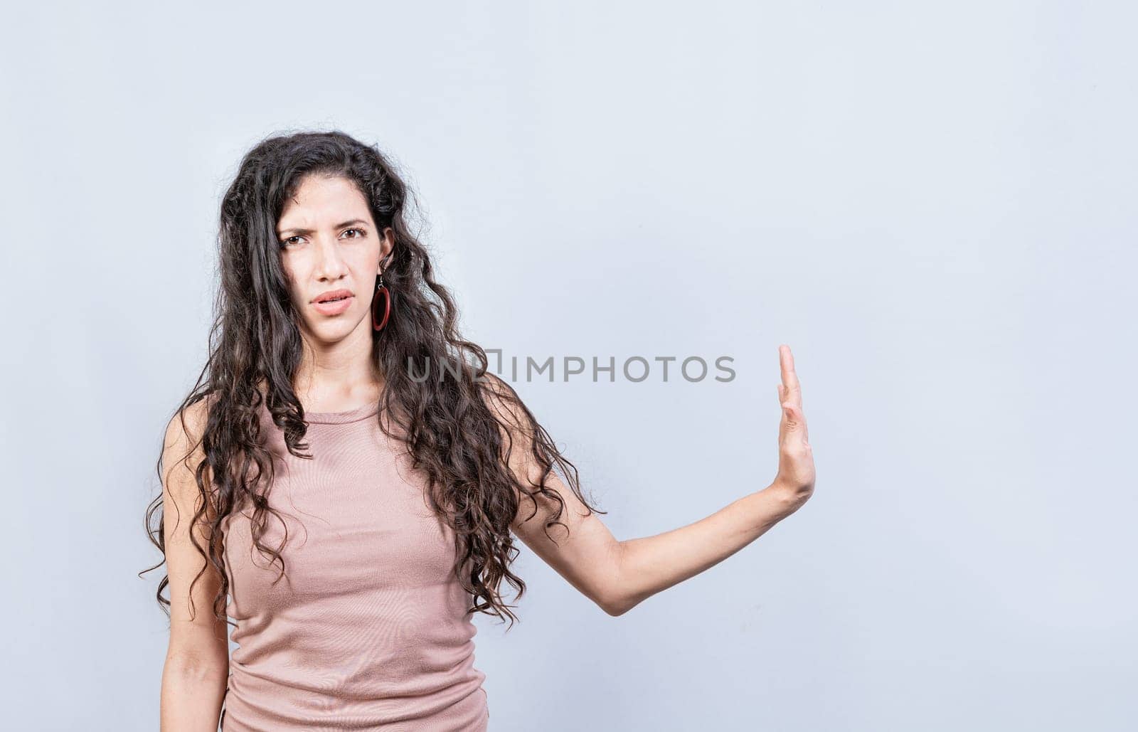 Displeased young woman rejecting with palm of hand isolated. Displeased girl making rejection gesture with palm of hand on white background.