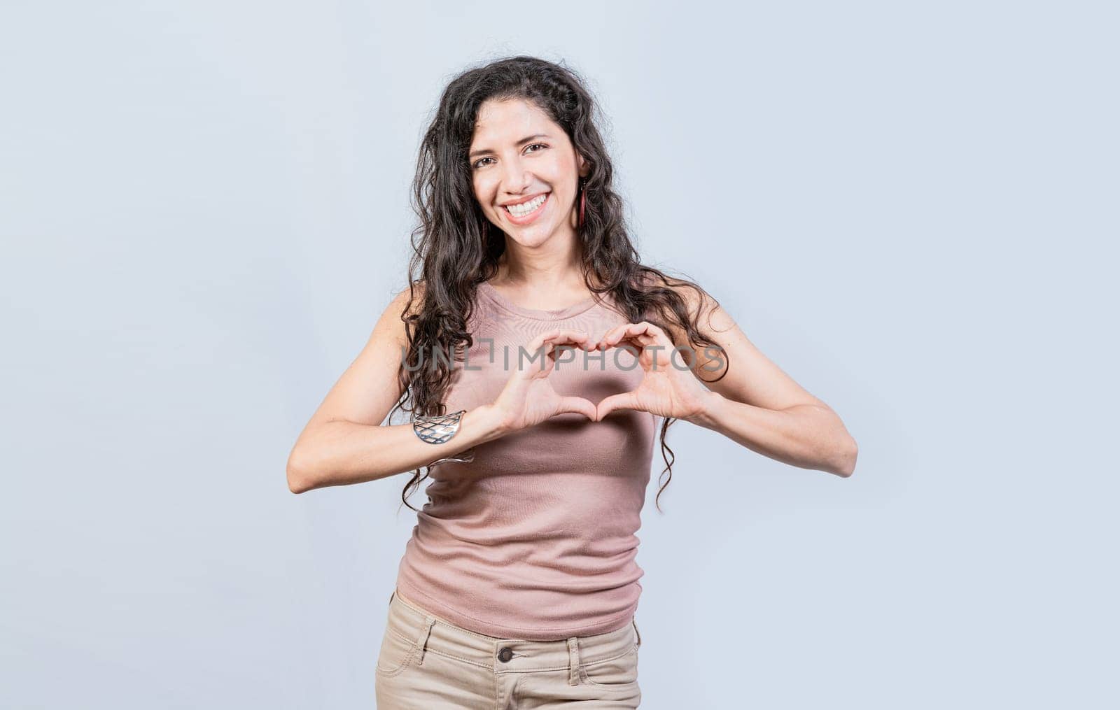 Smiling young woman making heart shape with her hands. Teen girl making heart shape with her hands, Happy girl making heart shape with hands isolated