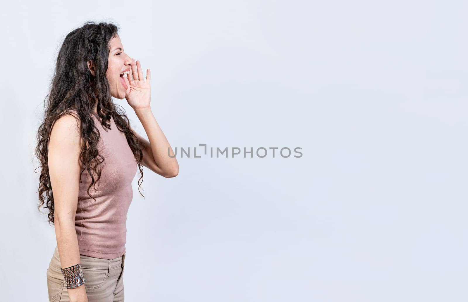 Beautiful girl shouting a promotion isolated. Side profile young woman shouting an announcement. Latin woman shouting an advertisement by isaiphoto