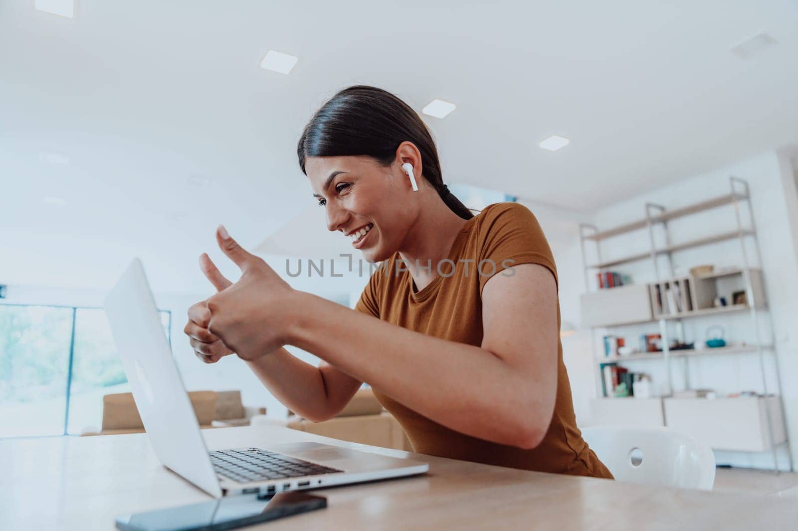 Woman sitting in living room using laptop look at cam talk by video call with business friend relatives, head shot. Job interview answering questions. by dotshock