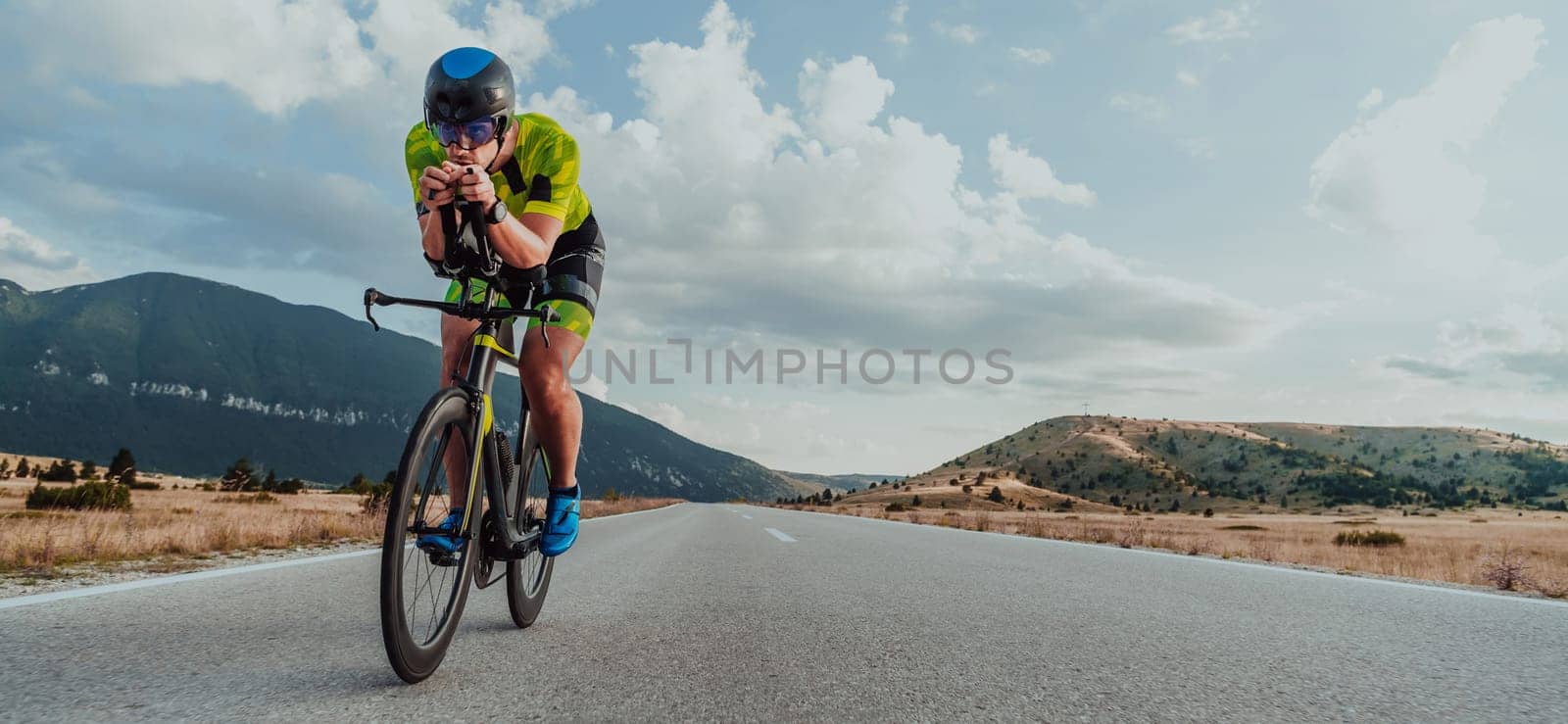 Full length portrait of an active triathlete in sportswear and with a protective helmet riding a bicycle. Selective focus by dotshock