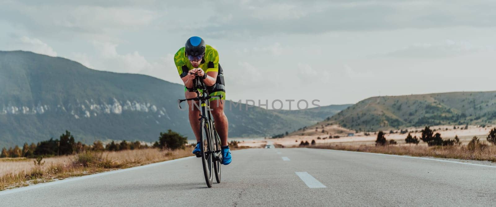 Full length portrait of an active triathlete in sportswear and with a protective helmet riding a bicycle. Selective focus by dotshock