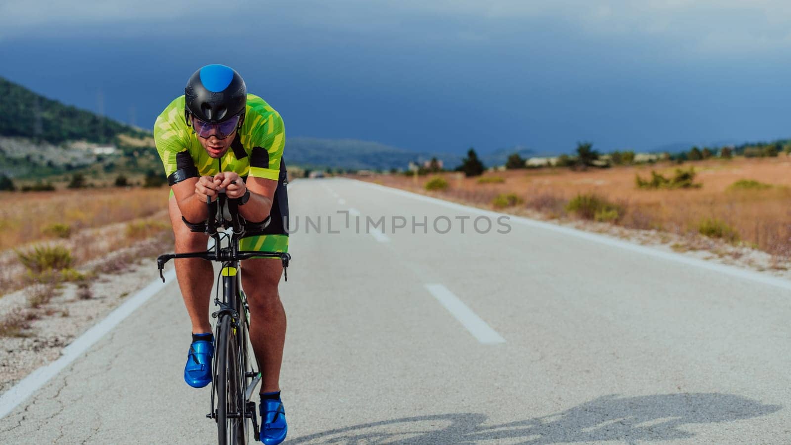 Full length portrait of an active triathlete in sportswear and with a protective helmet riding a bicycle. Selective focus by dotshock