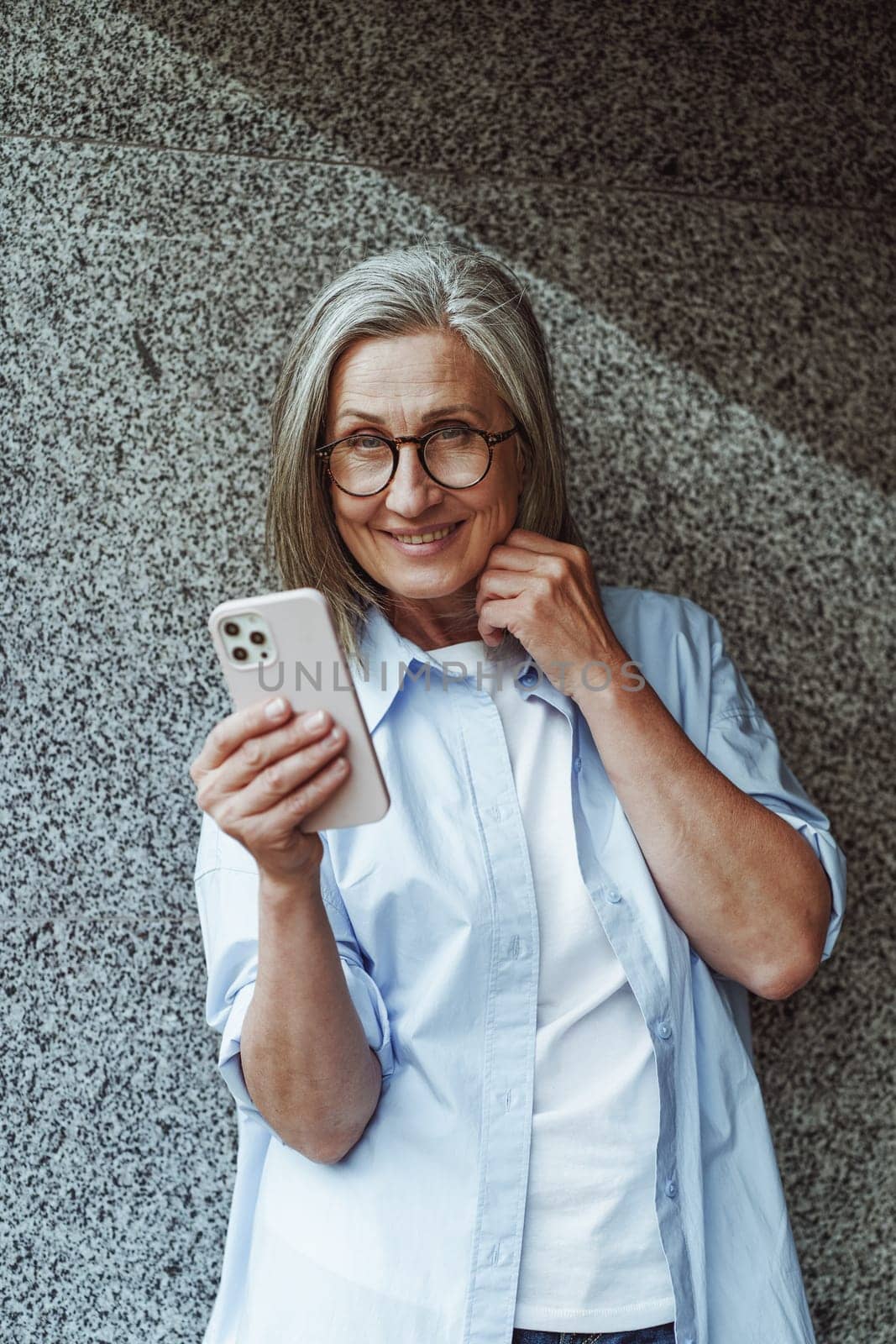 Concept of communication in old age, mature senior woman using mobile phone for texting and internet messengers. Woman's active engagement with technology and desire to stay connected in digital age. by LipikStockMedia