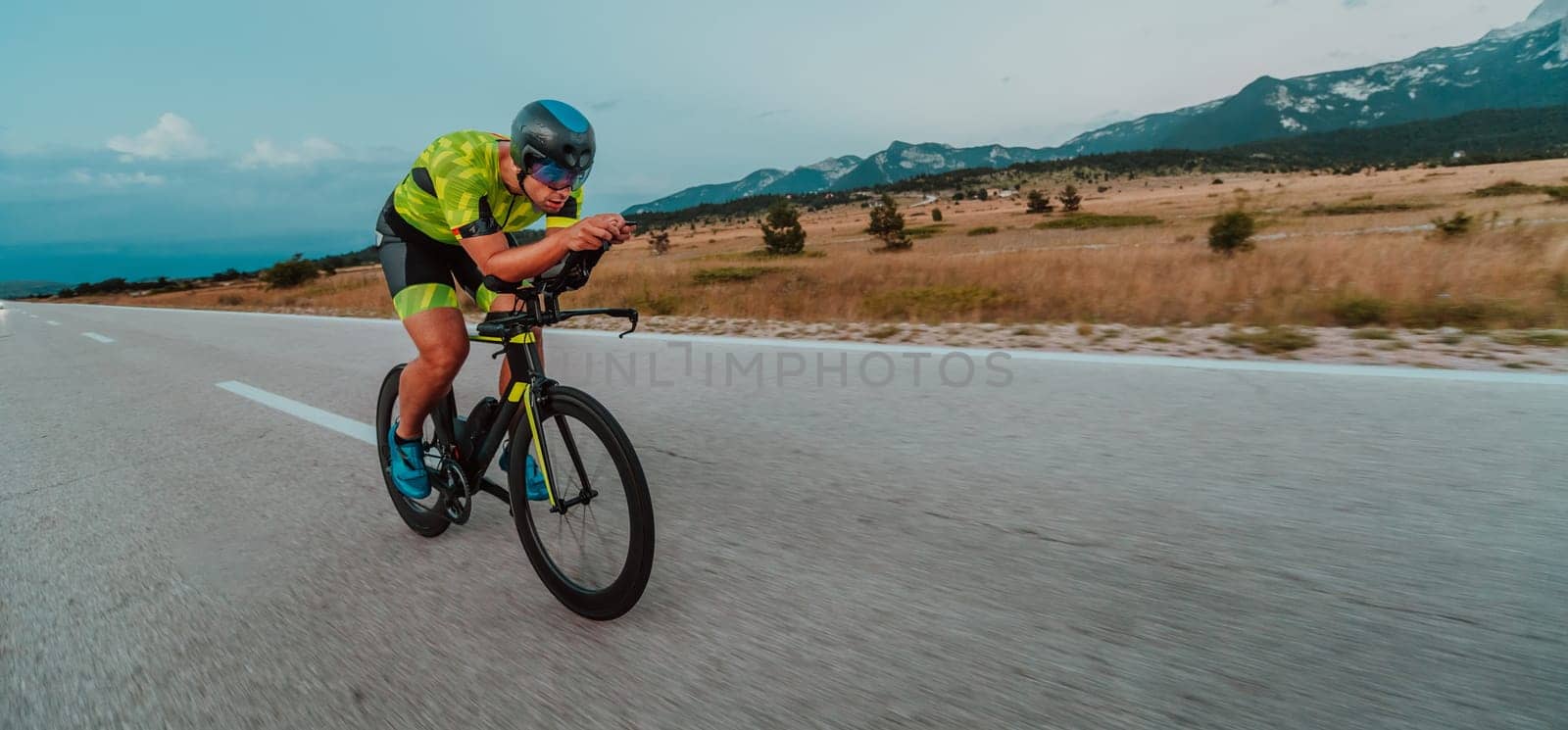 Full length portrait of an active triathlete in sportswear and with a protective helmet riding a bicycle. Selective focus by dotshock