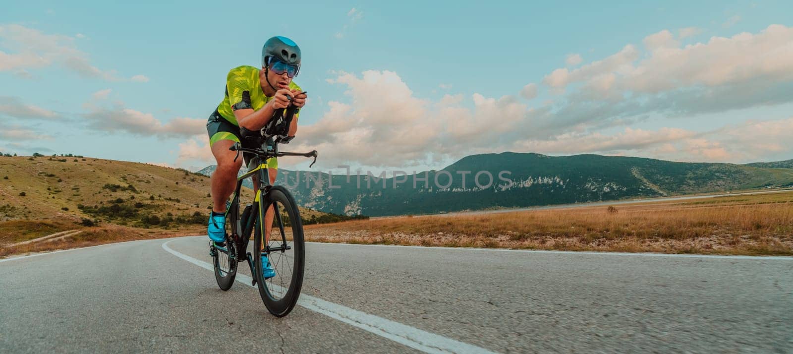 Full length portrait of an active triathlete in sportswear and with a protective helmet riding a bicycle. Selective focus.