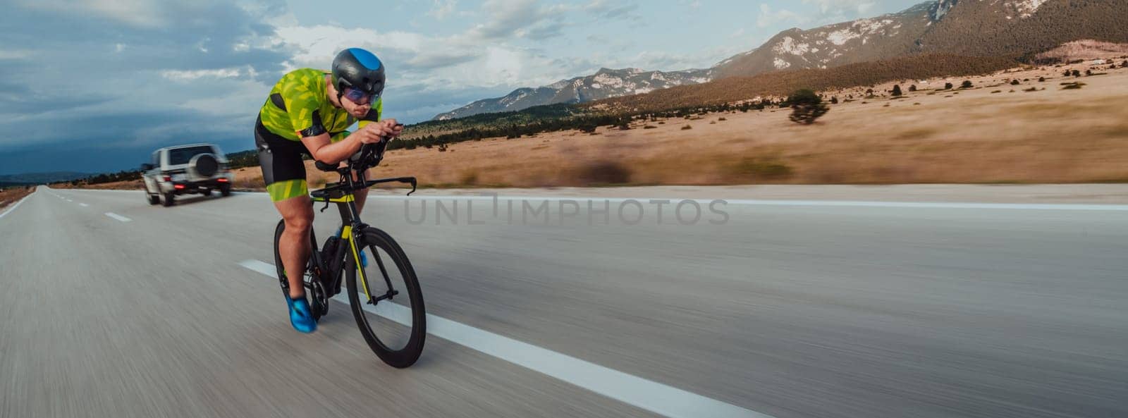 Full length portrait of an active triathlete in sportswear and with a protective helmet riding a bicycle. Selective focus by dotshock