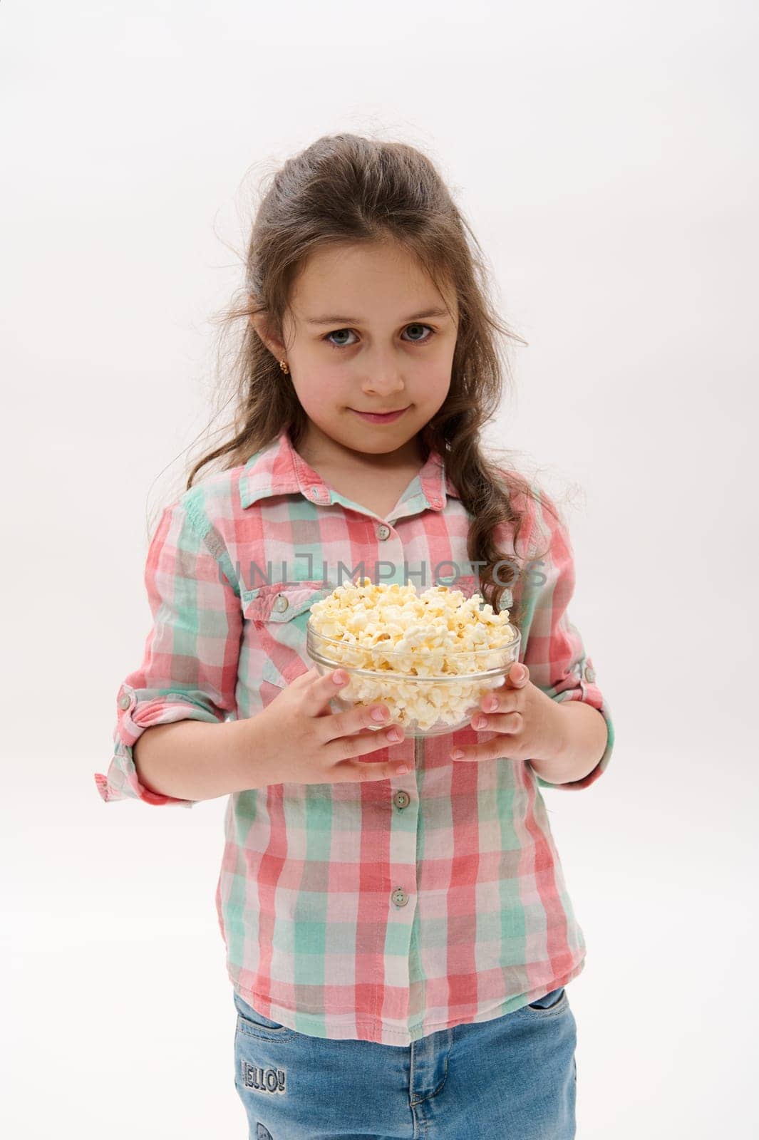 Portrait on white background of a lovely Caucasian little child girl holding a bowl of pop corn and smiling at camera by artgf