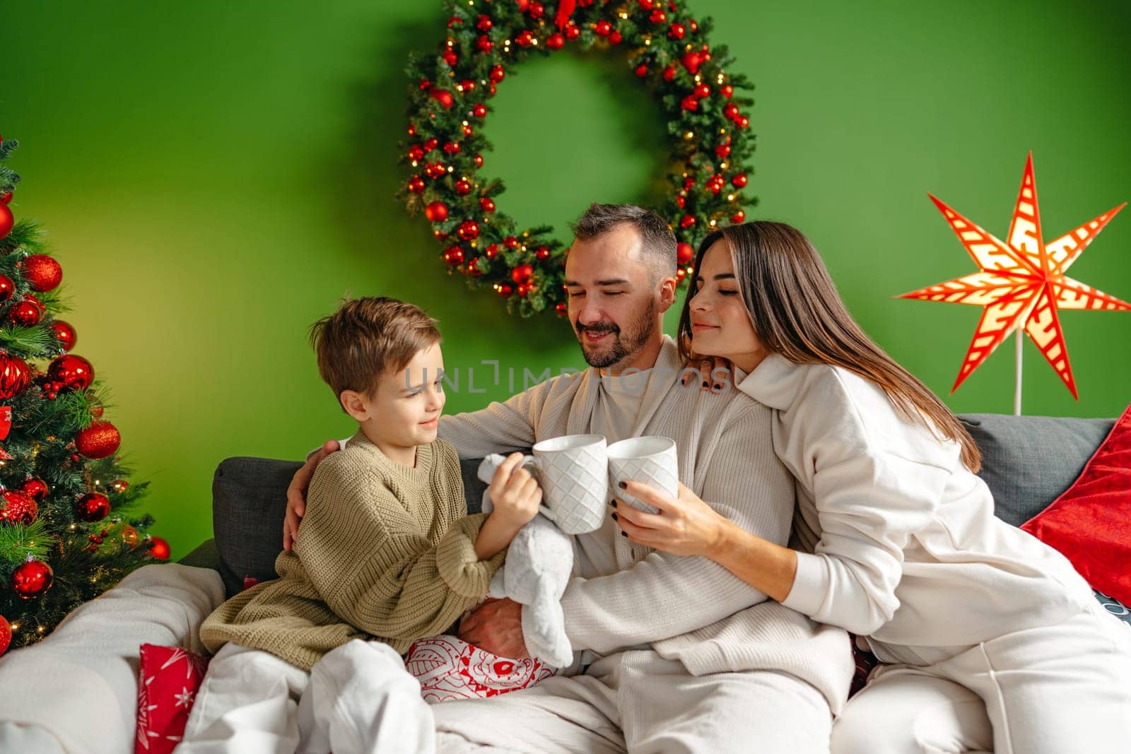 Happy young family sitting on sofa and relaxing at home at Christmas time