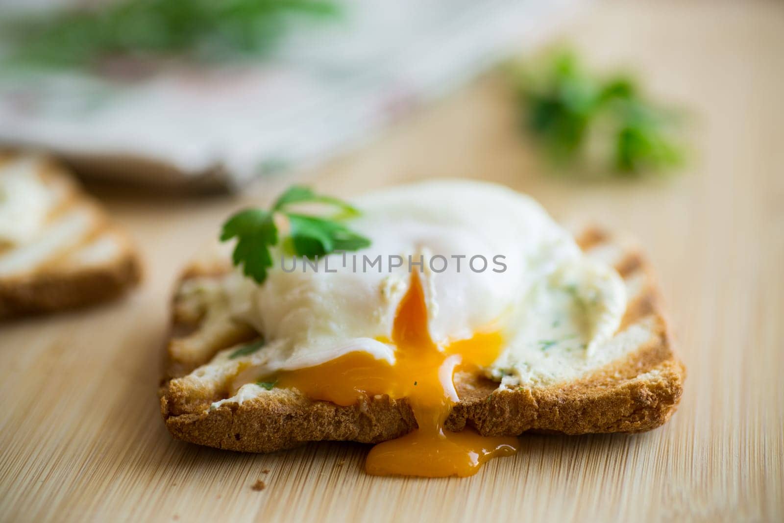 Fried toast bread with spread and poached egg, on a wooden table. Quick breakfast.