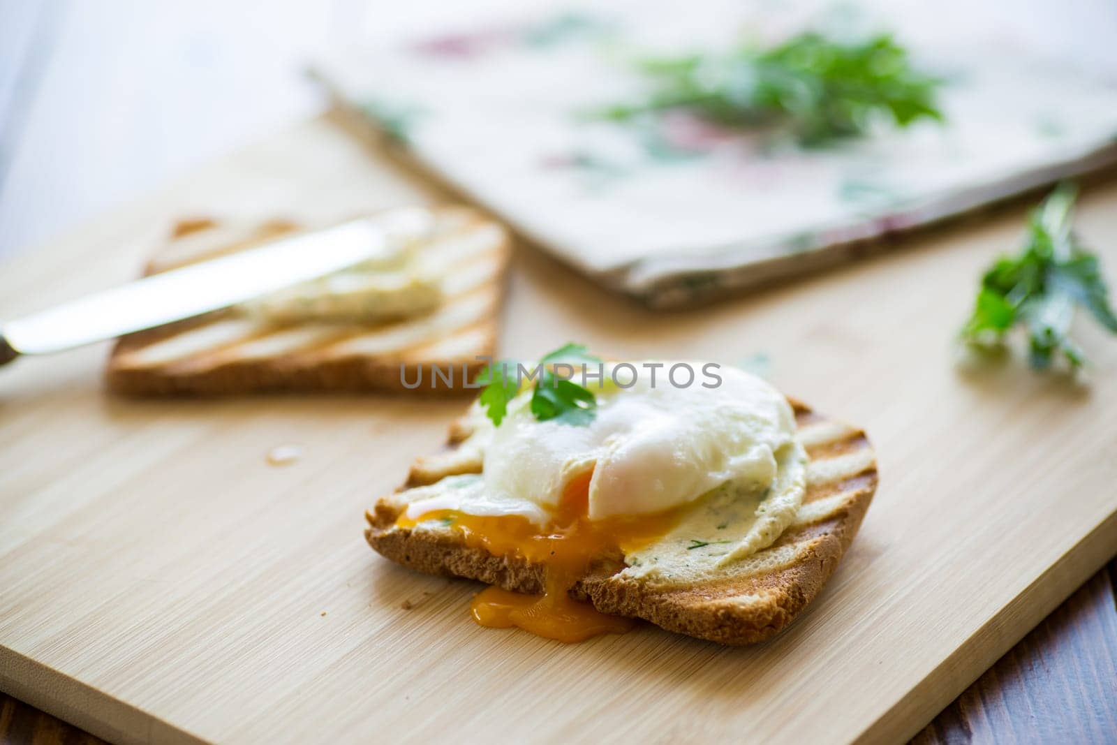 Fried toast bread with spread and poached egg, on a wooden table. Quick breakfast.