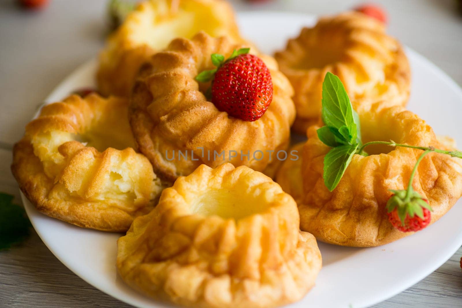 Cooked sweet curd cupcakes with fresh strawberries and mint on a wooden table.