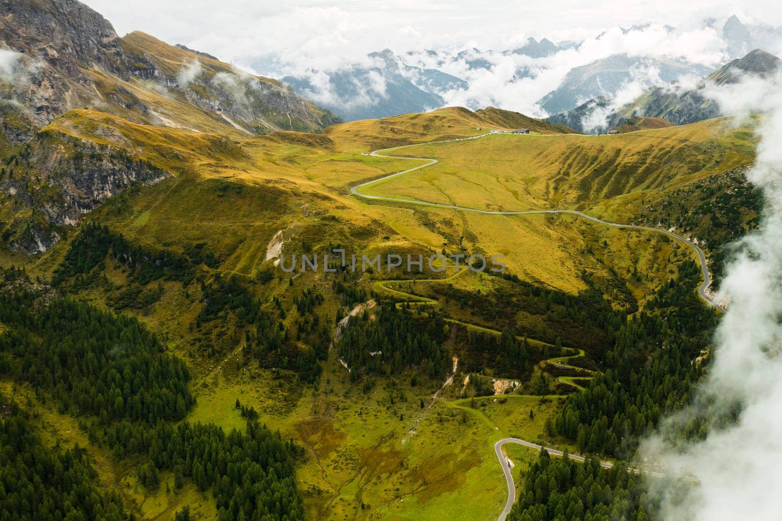 Surreal ambiance of the Dolomite Alps as clouds descend upon the valley, blanketing the landscape, including the iconic Giau Pass, in an enchanting mist.
