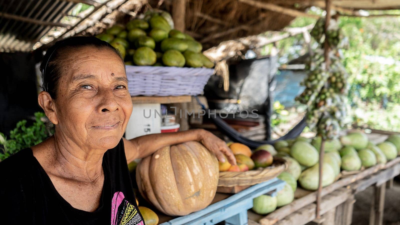 Old fruit seller at a farmers' market smiling by cfalvarez