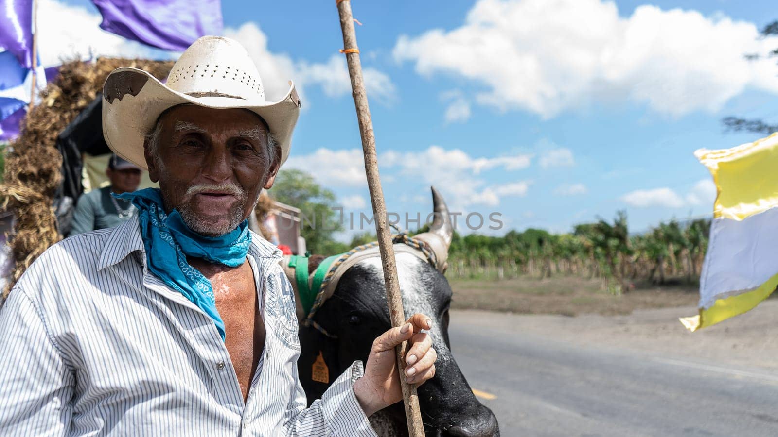 An elderly Latino man with hat and vitiligo being transported in a cart on a road by cfalvarez