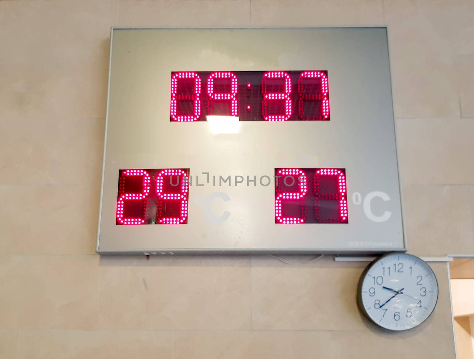 LED display panel with air and water temperature, round classic clock on the wall.
