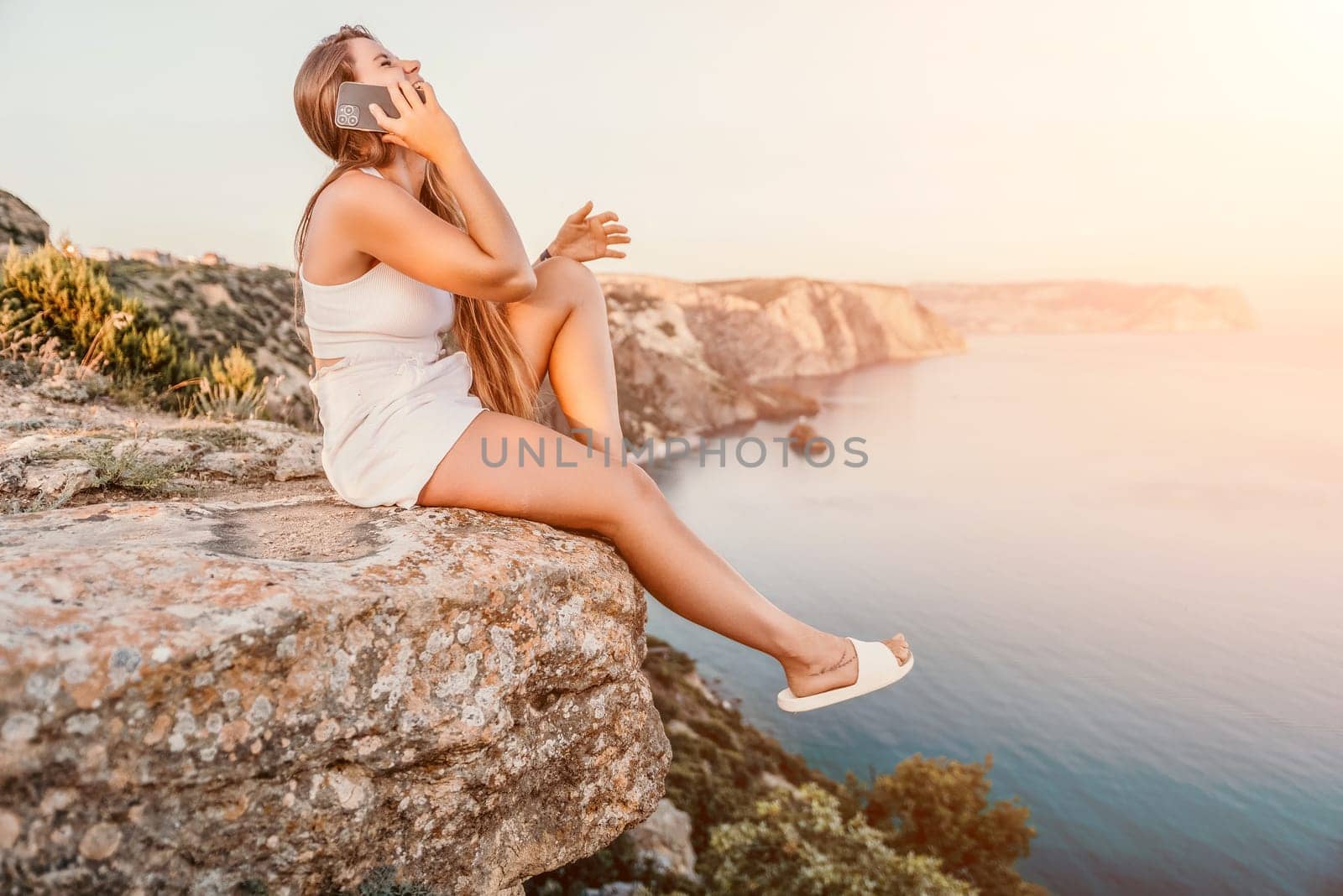 Woman travel sea. Happy tourist in hat enjoy taking picture outdoors for memories. Woman traveler posing on the beach at sea surrounded by volcanic mountains, sharing travel adventure journey by panophotograph