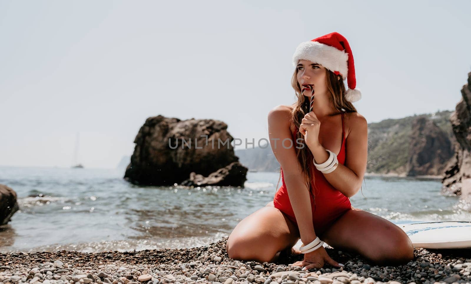 Woman travel sea. Happy tourist enjoy taking picture on the beach for memories. Woman traveler in Santa hat looks at camera on the sea bay, sharing travel adventure journey by panophotograph