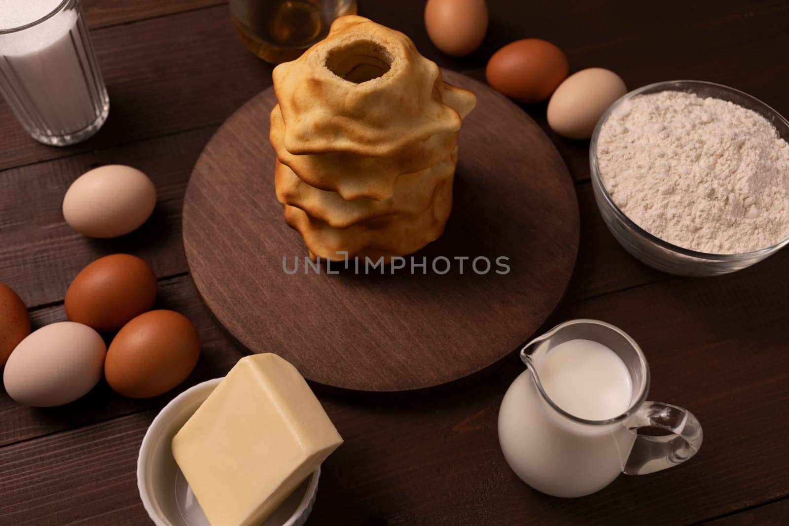 Baumkuchen, sakotis ,sekacz at center and ingredients around on wooden table, traditional sweet spit cake made of butter, eggs, flour, sugar. Horizontal plane. High quality photo